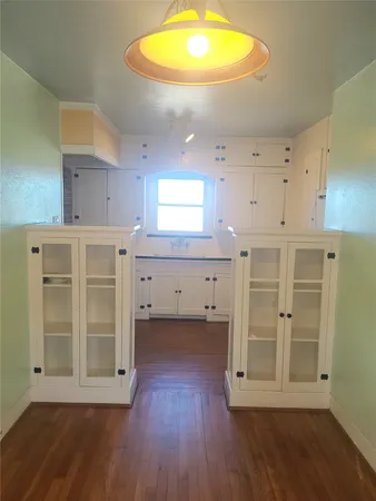 a kitchen with wooden floors and white cabinets