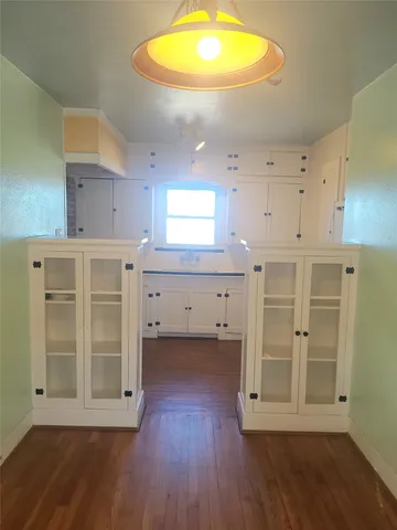 a kitchen with wooden floors and white cabinets