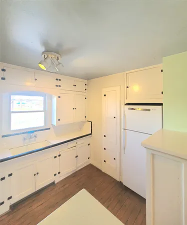 a kitchen with cabinets and wooden floor