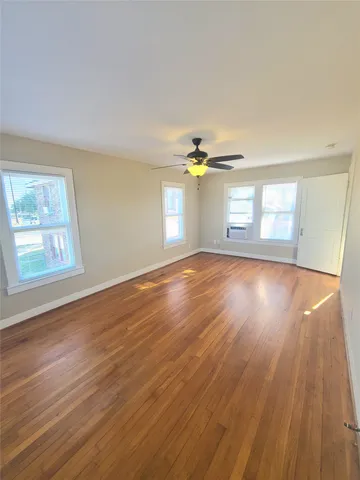a view of an empty room with wooden floor and window