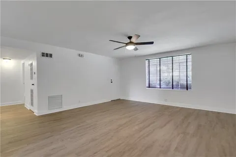 a view of an empty room with a window and wooden floor