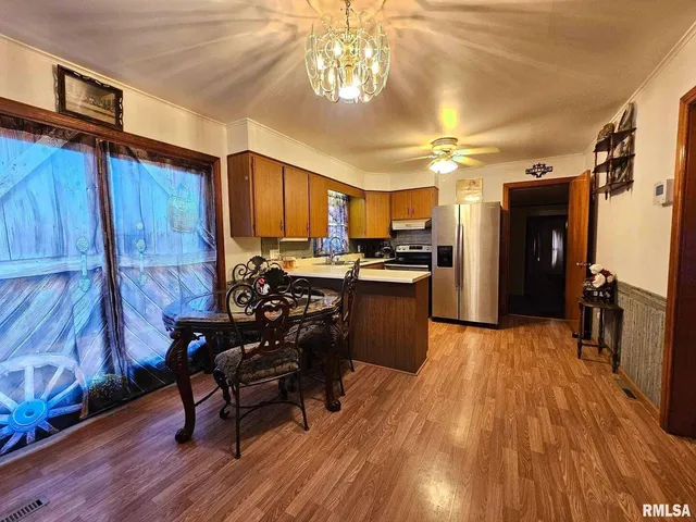 a kitchen with a refrigerator a stove a sink dishwasher and a dining table with wooden floor