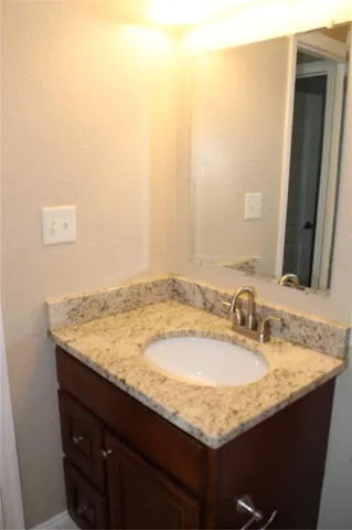 a bathroom with a granite countertop sink and a mirror