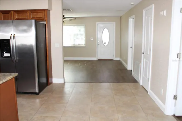 an empty room with windows mirror and a kitchen