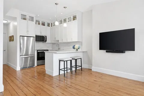 a kitchen with a refrigerator a microwave a stove and a dining table with wooden floor