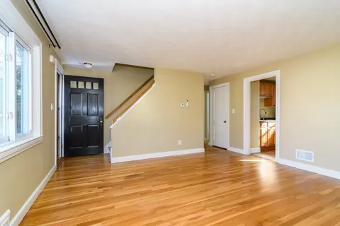 a view of an empty room with window and wooden floor