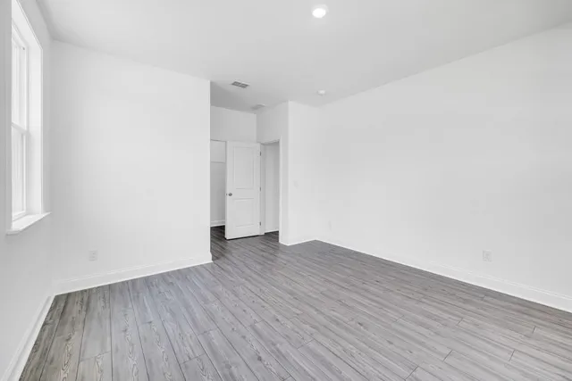 a view of empty room with wooden floor and windows