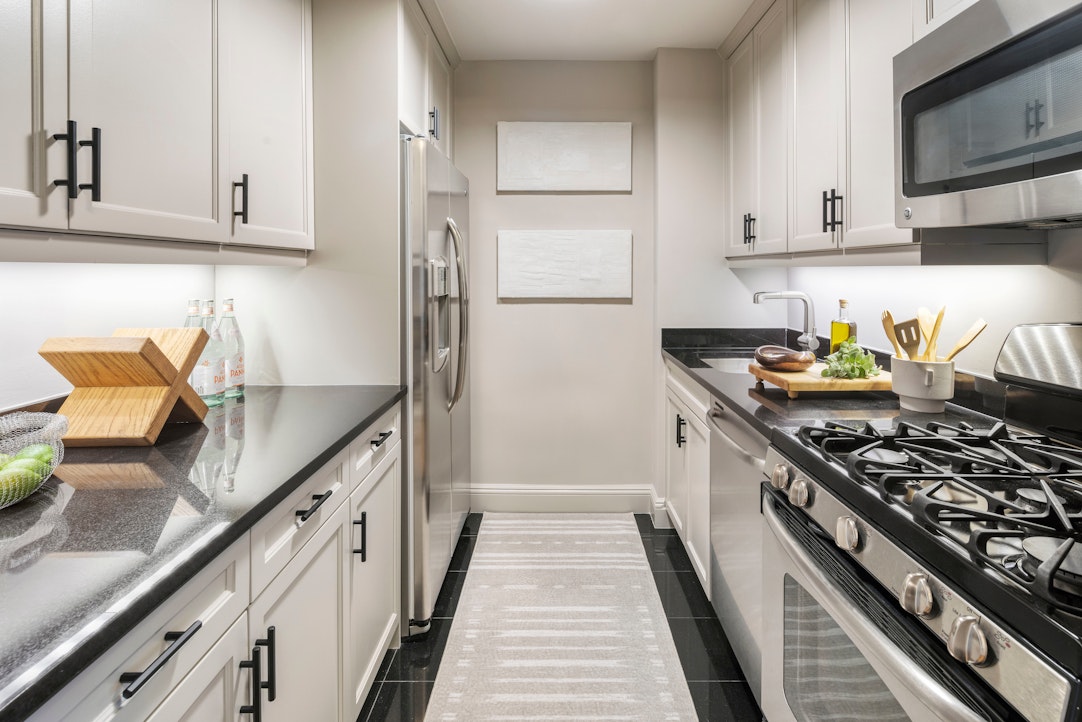 155 West 68th Street, Unit 1210 Manhattan, NY 10023 - Photo 4 of 17 a kitchen with stainless steel appliances granite countertop a stove a refrigerator and a counter space