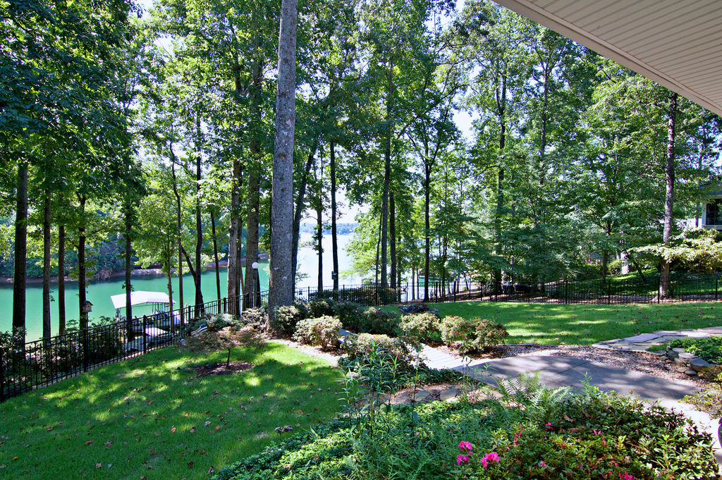 11001 Lake Ridge Lane Seneca, SC 29672 - Photo 43 of 50 Towering trees frame serene lake views from this grassy, fenced backyard with a stone path.