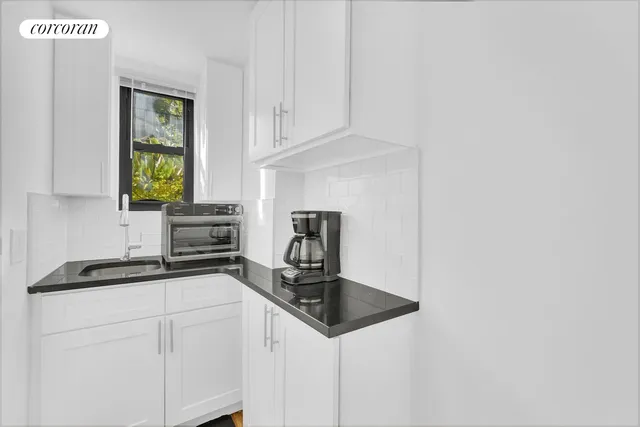 a kitchen with granite countertop a sink cabinets and window