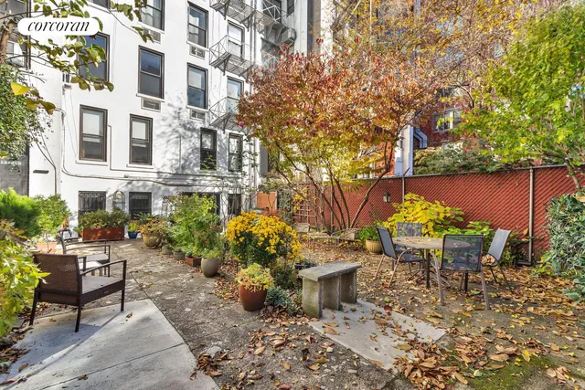 a backyard with table and chairs potted plants and a large tree