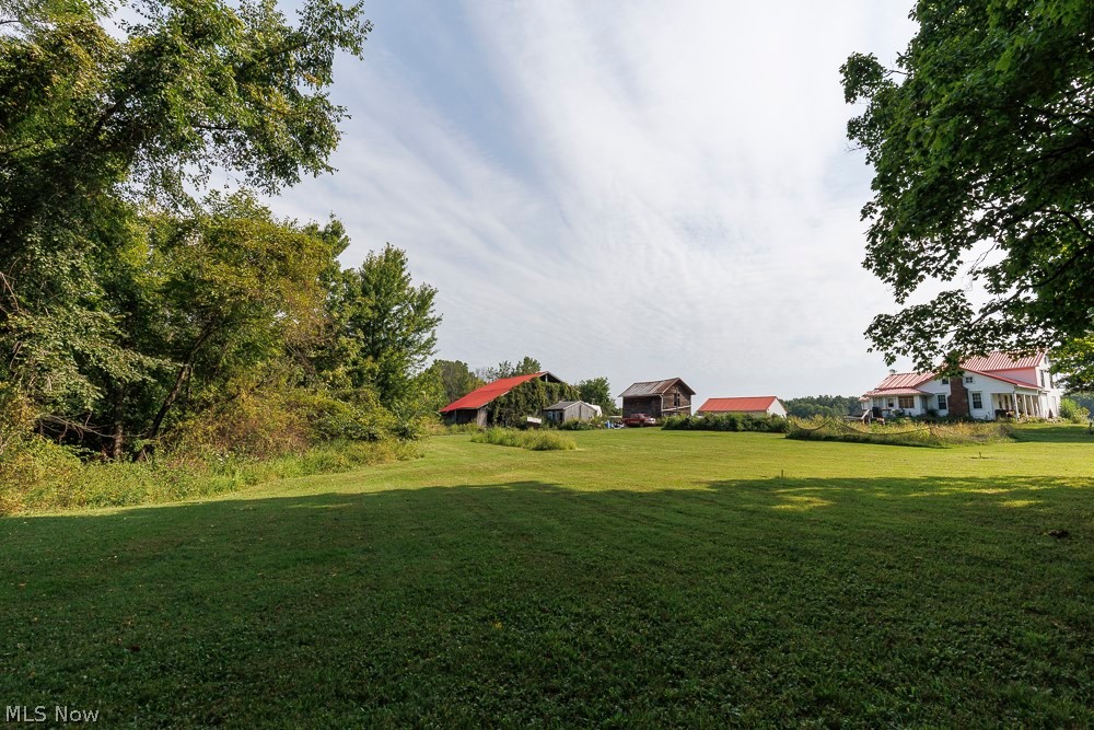 5366 Zenobia Road Wakeman, OH 44889 - Photo 20 of 25 Expansive lawn with mature trees, multiple outbuildings, and a two-story residence featuring a red roof