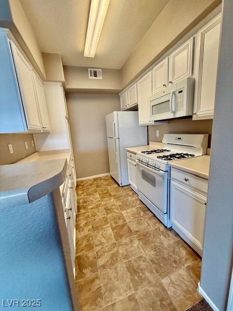 7155 South Durango Drive, Unit 306 Las Vegas, NV 89113 - Photo 4 of 19 Kitchen featuring white appliances, white cabinetry, a textured ceiling, and light countertops