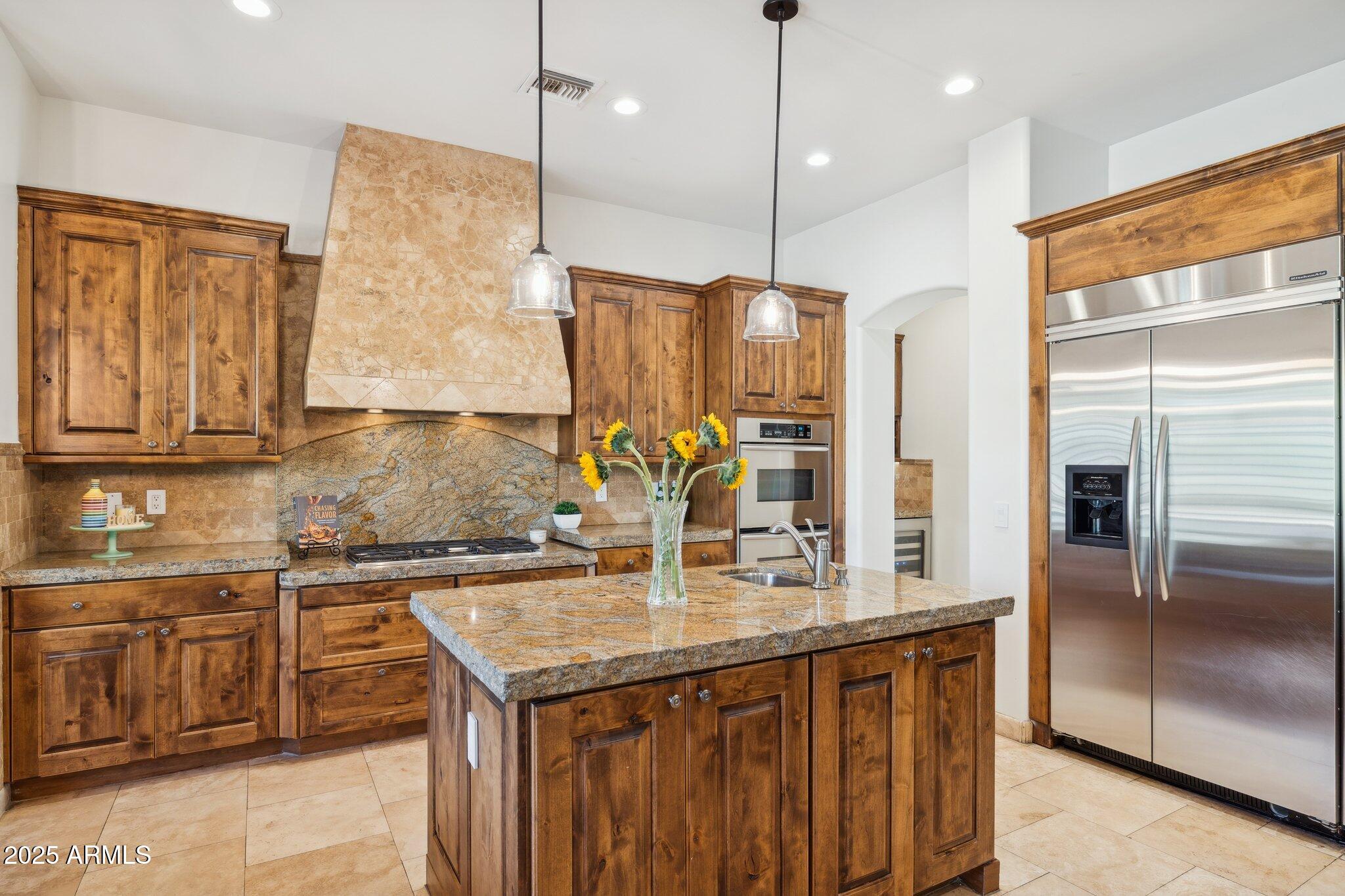 a kitchen with stainless steel appliances granite countertop a sink a refrigerator and a wooden cabinets