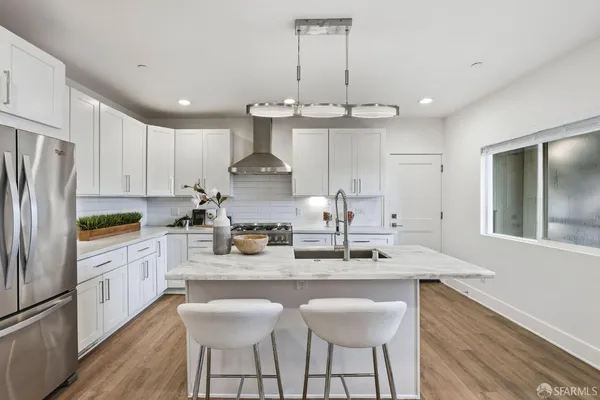 a kitchen with stainless steel appliances a sink stove a refrigerator and white cabinets with wooden floor