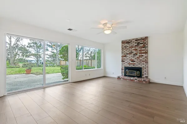 an empty room with floor to ceiling windows and fireplace