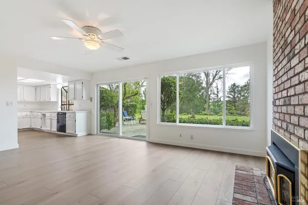 a view of empty room with wooden floor and fan