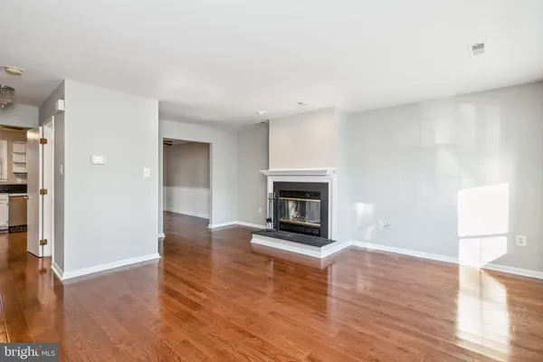 a view of an empty room with wooden floor fireplace and a window
