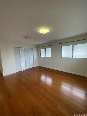 a view of empty room with wooden floor and fan