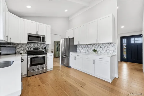 a kitchen with granite countertop a stove a sink and a refrigerator