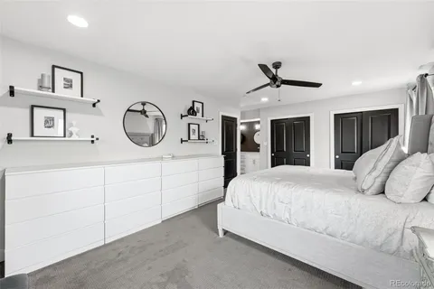 a spacious bedroom with a bed a mirror and window