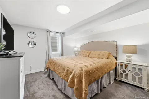 a bedroom with a bed and a flat tv screen on dresser