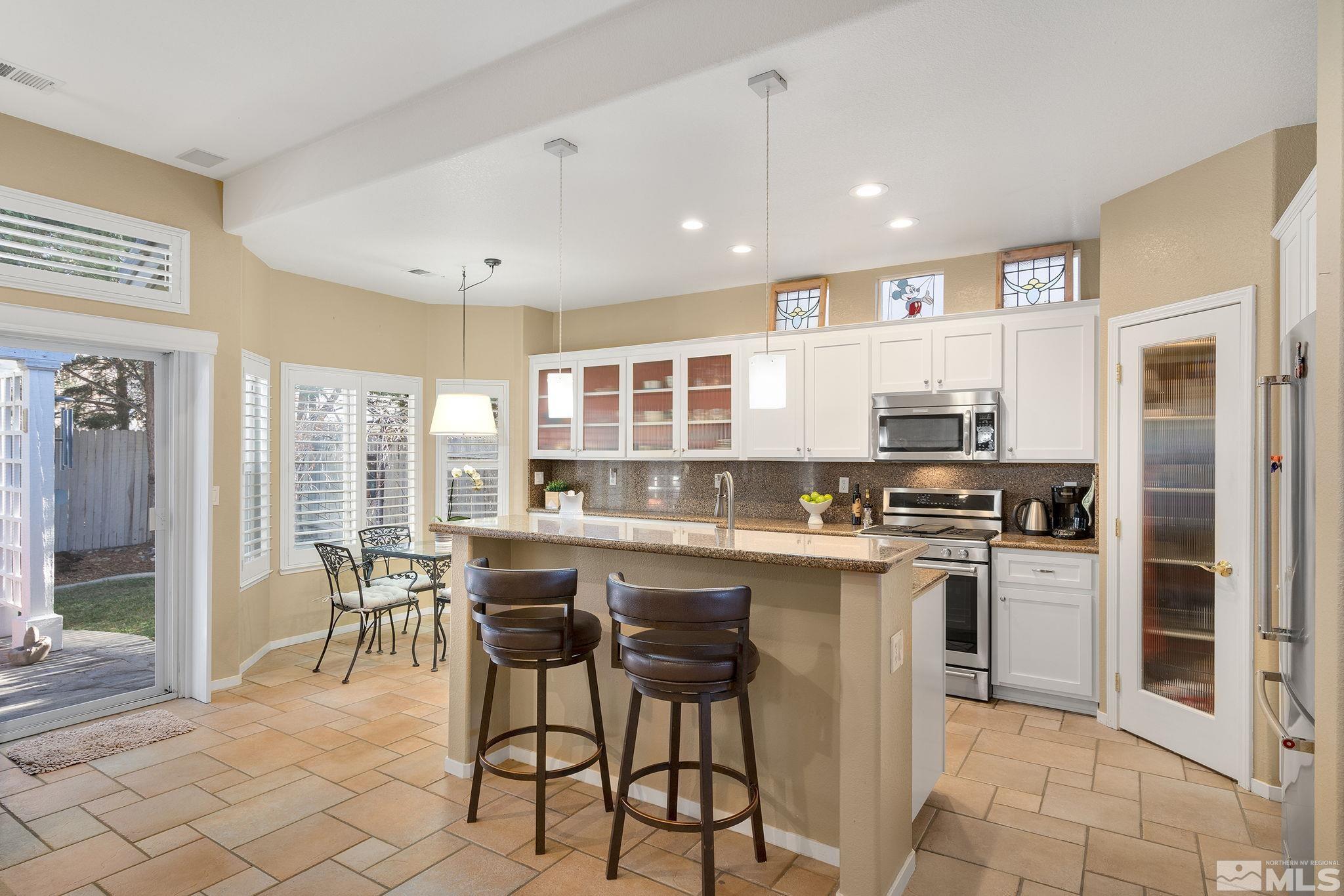 1700 Comanche Moon Drive Reno, NV 89521 - Photo 15 of 34 a kitchen with stainless steel appliances granite countertop a stove top oven a sink dishwasher a dining table and chairs with wooden floor