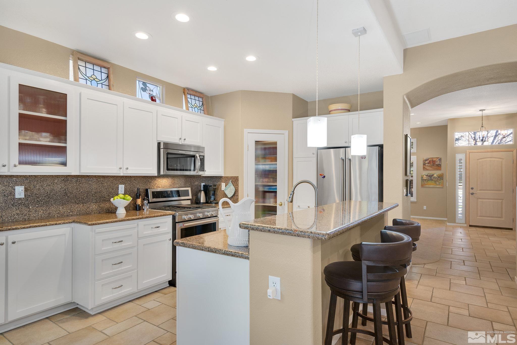 1700 Comanche Moon Drive Reno, NV 89521 - Photo 16 of 34 a kitchen with stainless steel appliances kitchen island granite countertop a stove top oven a sink a dining table and chairs