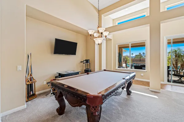 a room with furniture pool table flat screen tv and windows