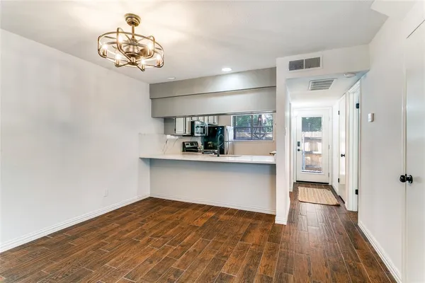 a view of a hallway with wooden floor and a kitchen