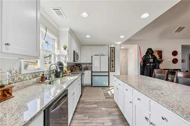 a large kitchen with stainless steel appliances kitchen island a large counter top a stove a chimney a sink and a refrigerator