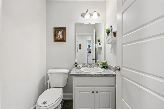 a bathroom with a granite countertop toilet sink and mirror