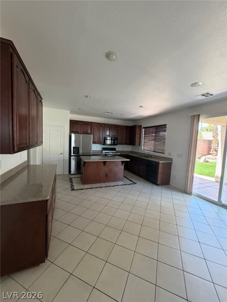 3862 Landing Ridge Place Las Vegas, NV 89135 - Photo 3 of 26 A spacious kitchen with an island, granite counters, and tile flooring, opening to an outdoor patio.