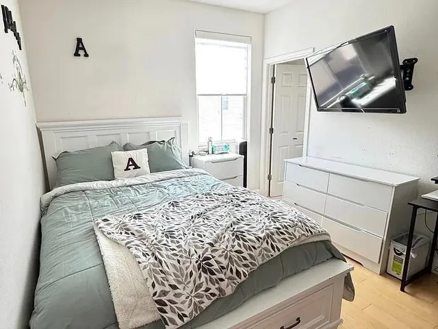a bedroom with a bed a flat screen tv and window