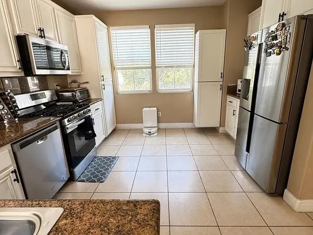 a kitchen with stainless steel appliances a stove a refrigerator a sink a window and a counter