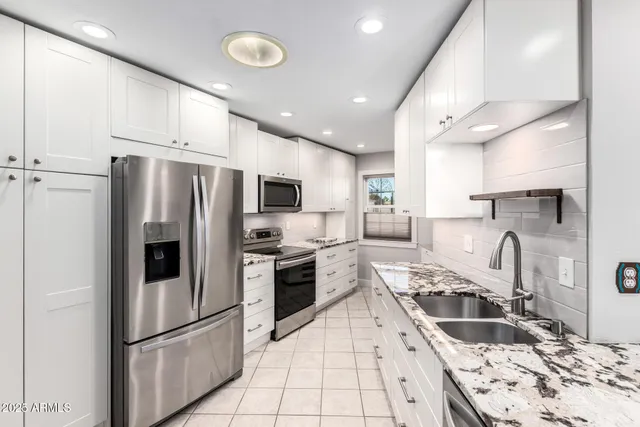 a kitchen with stainless steel appliances granite countertop a refrigerator sink and stove