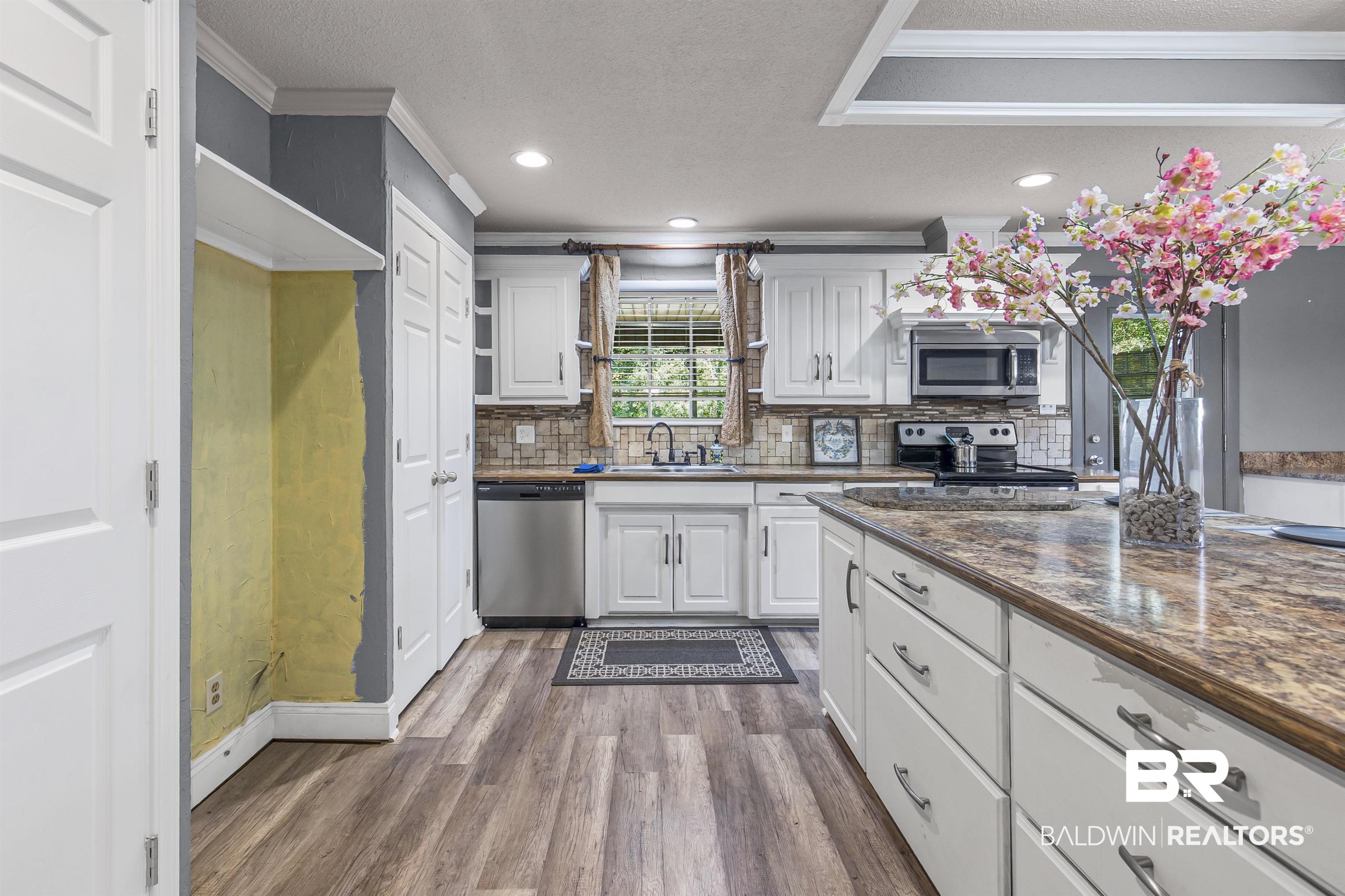 36 Ridgeview Drive Mobile, AL 36611 - Photo 5 of 20 Kitchen featuring white cabinetry, ornamental molding, dark wood-style flooring, tasteful backsplash, and stainless steel appliances