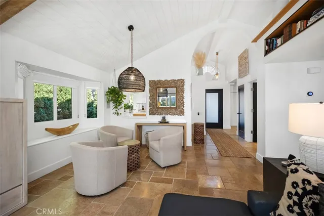 a living room with furniture a chandelier a large window and potted plants