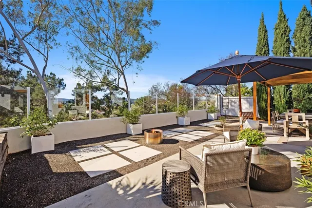 a view of a patio with couches table and chairs under an umbrella with a barbeque