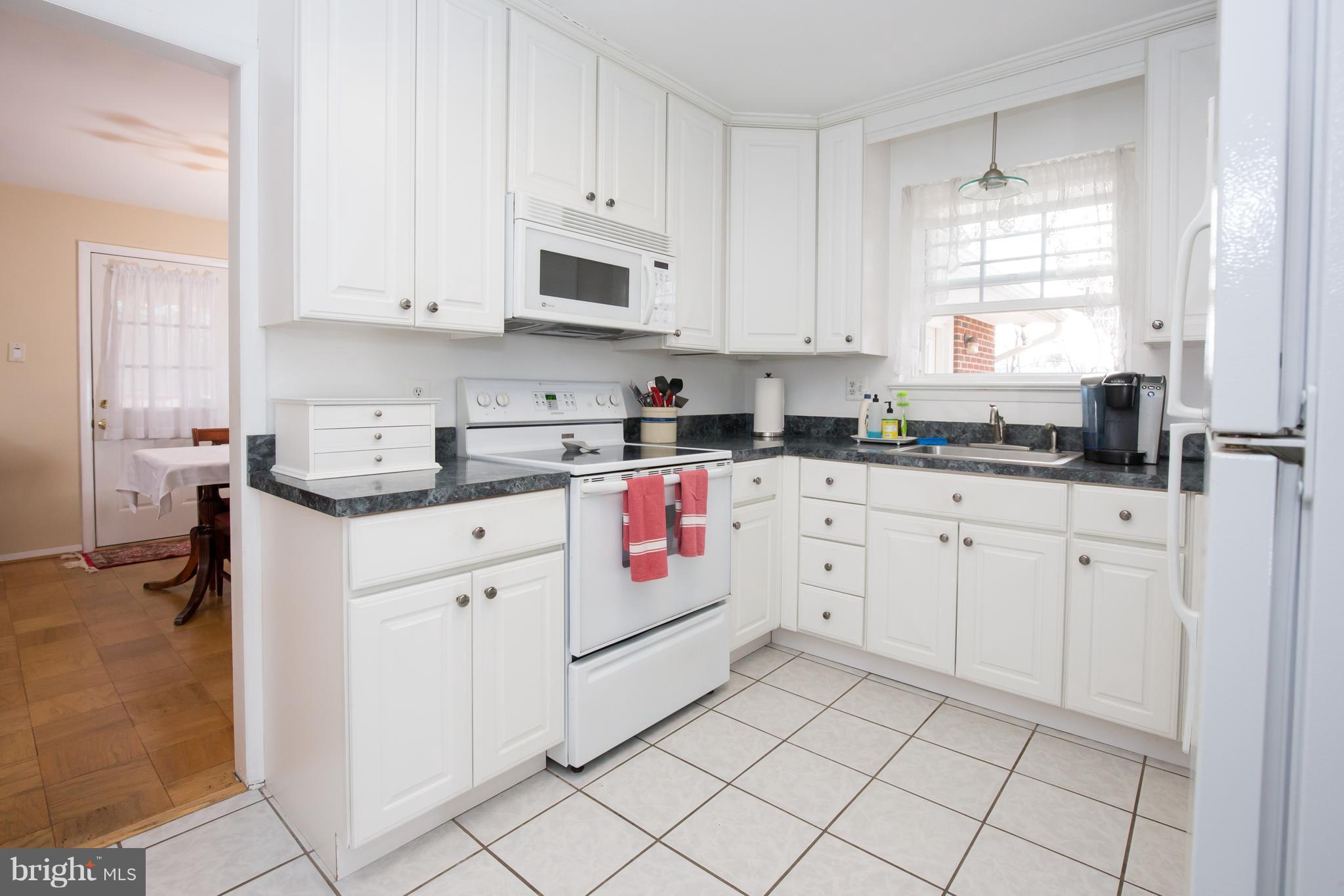 5227 Milland Street Springfield, VA 22151 - Photo 12 of 28 a kitchen with stainless steel appliances granite countertop white cabinets sink and window