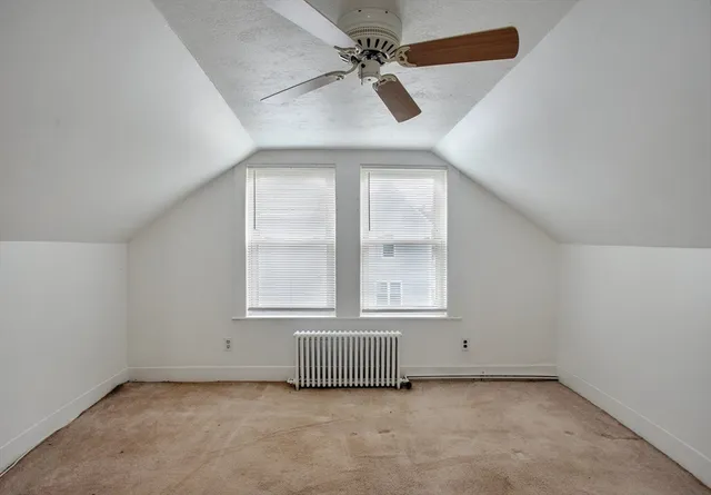 an empty room with chandelier fan and windows