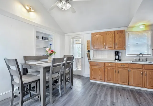 a kitchen with stainless steel appliances granite countertop a dining table chairs a sink and dishwasher a refrigerator with wooden floor