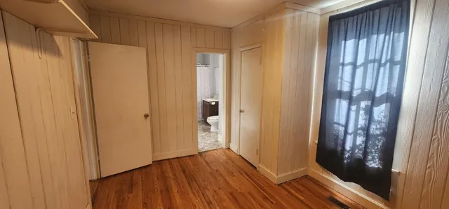 a view of a hallway with wooden floor and a bathroom