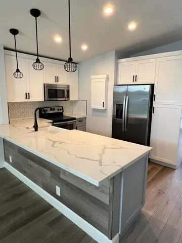 a kitchen with kitchen island a counter top space stainless steel appliances and cabinets
