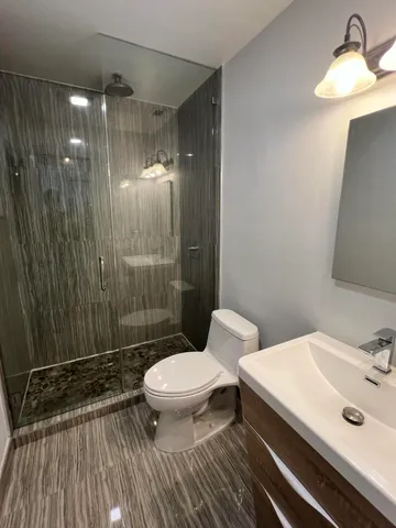 a bathroom with a sink a toilet a mirror and shower