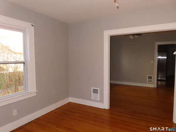 an empty room with wooden floor and windows