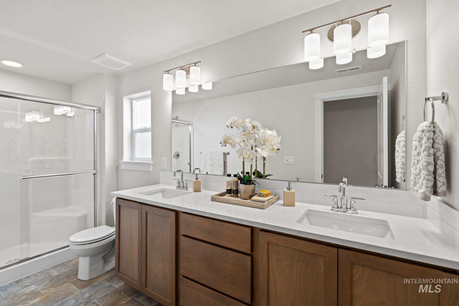 868 Adamite Road Kimberly, ID 83341 - Photo 10 of 22 Full bathroom featuring a shower stall, double vanity, and dark stone finish flooring