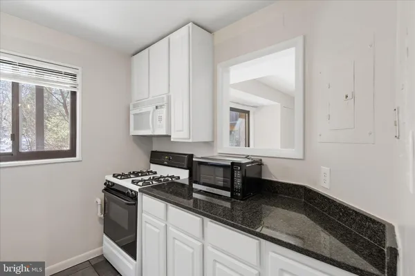 a kitchen with granite countertop a stove a sink and a window