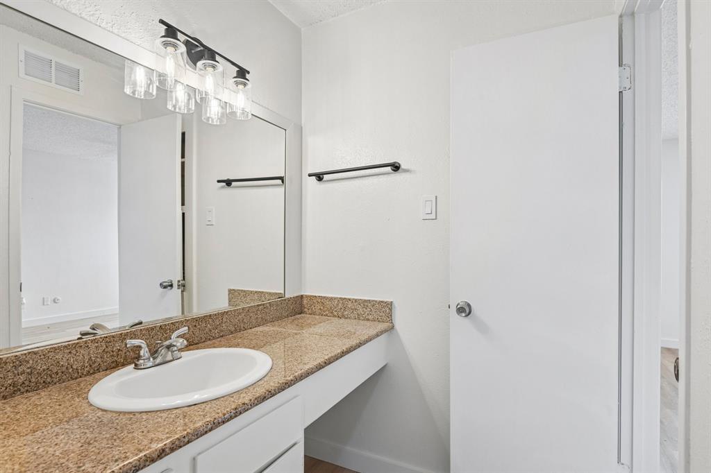 5300 Keller Springs Road, Unit 2055 Dallas, TX 75248 - Photo 13 of 24 Bathroom vanity featuring a speckled countertop, undermount sink, and chrome faucet