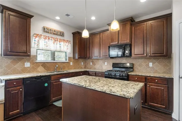 a kitchen with kitchen island granite countertop a sink window and cabinets
